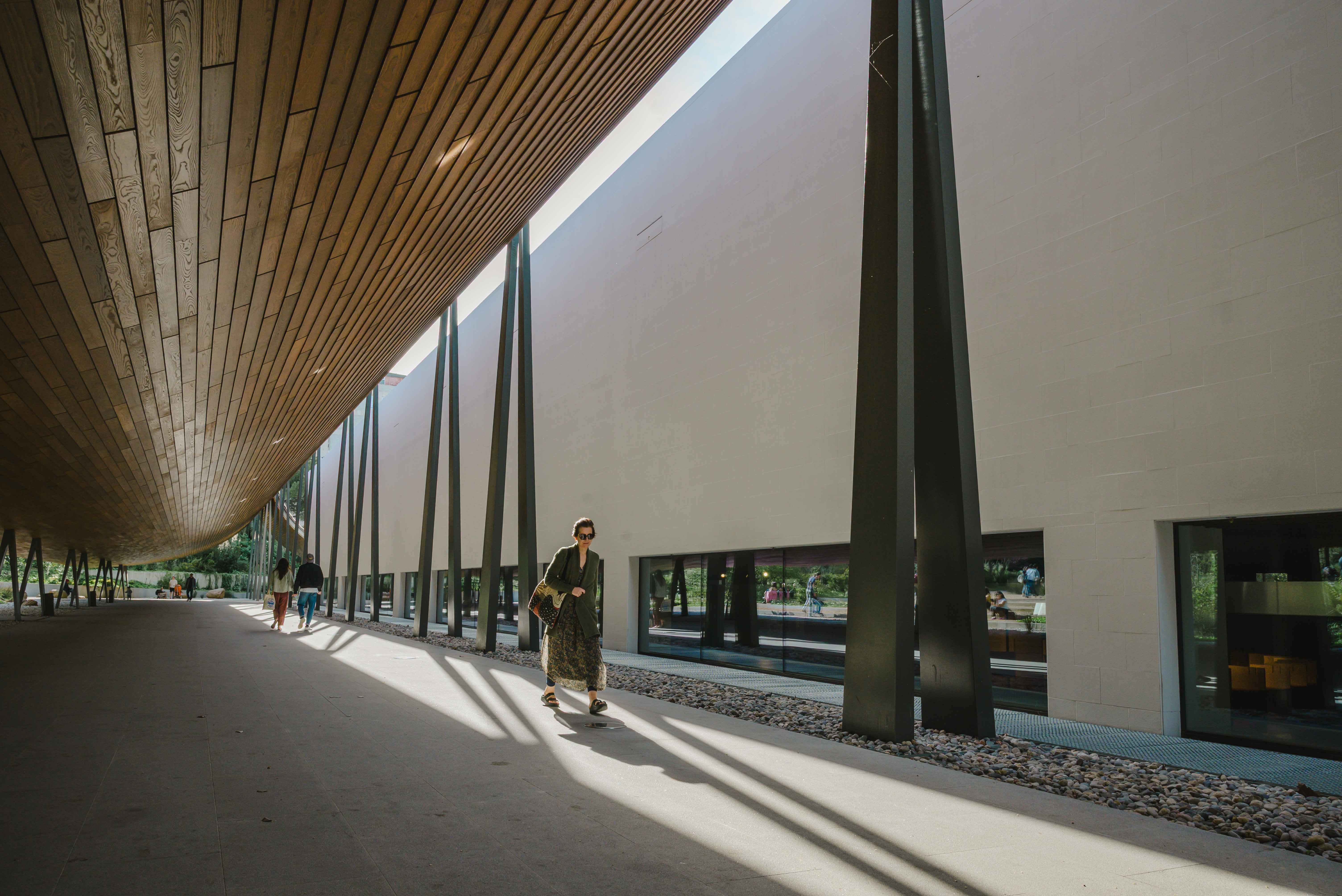 woman walking below a wooden structure
